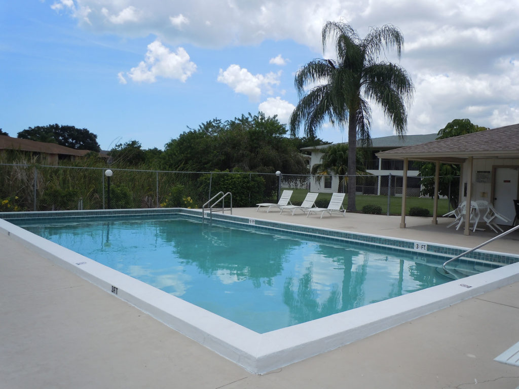 large rectangular inground pool surrounded by a nice community