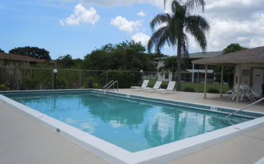 large rectangular inground pool surrounded by a nice community